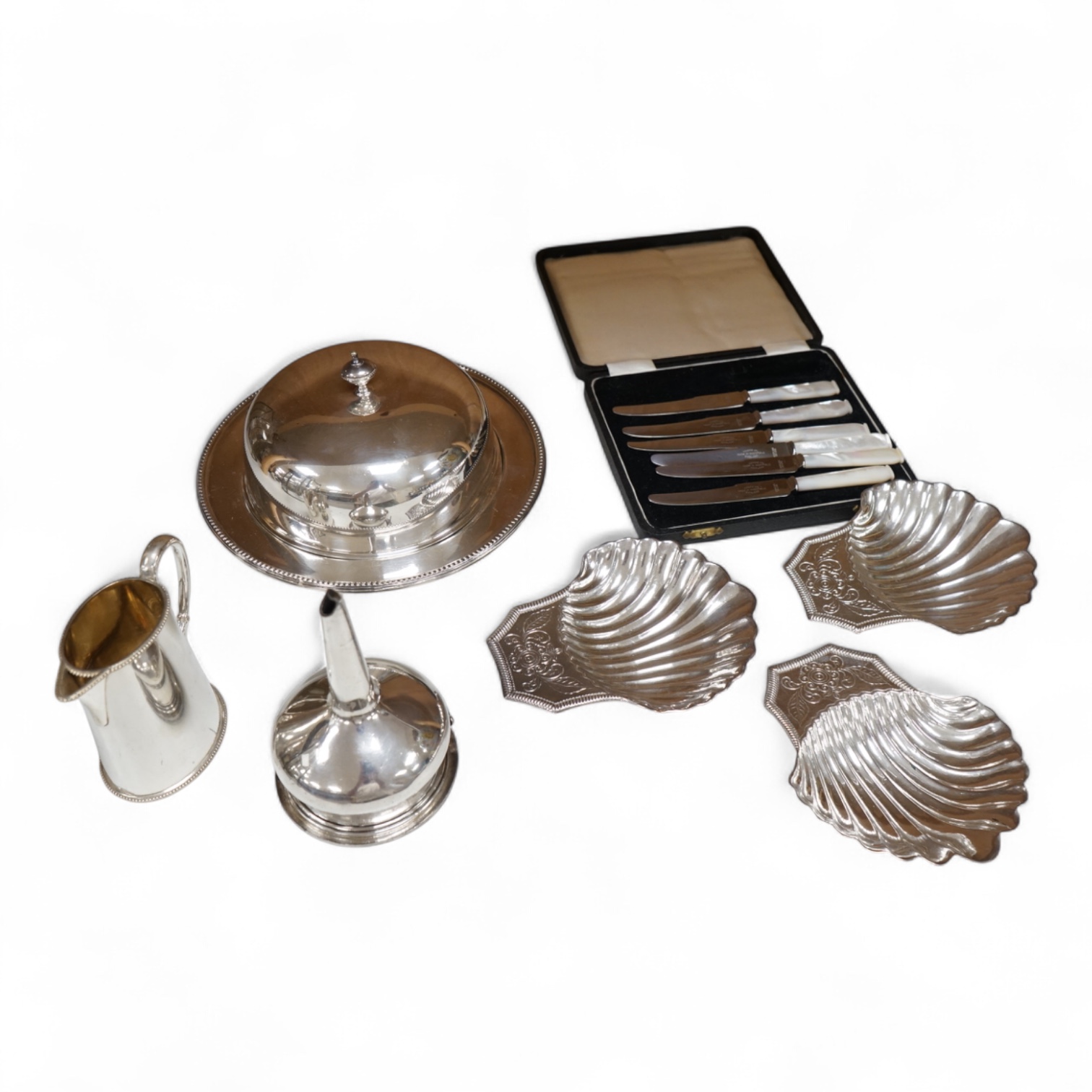 A Mappin plated muffin dish and six other plated items including three Old Sheffield plate butter shells, a wine funnel, Elkington & Co cream jug and cased set of tea knives.